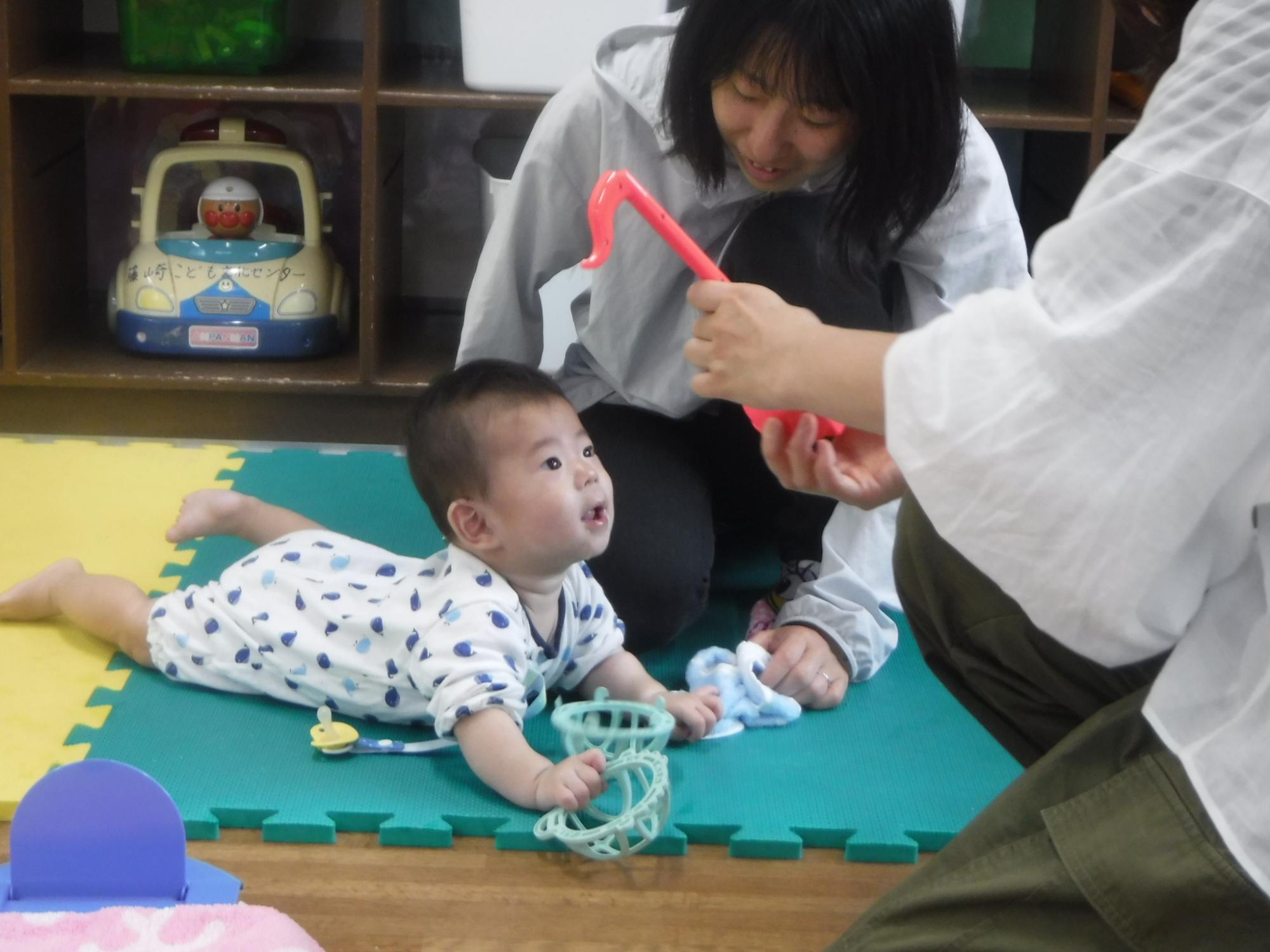 すまいるくらぶで音のでるおもちゃで遊ぶ幼児親子の写真