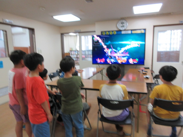 大画面でゲーム対戦をするこどもたちの写真