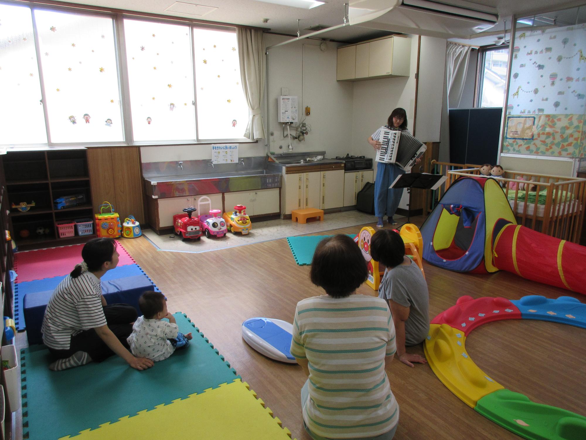 すまいるくらぶで演奏をきく親子の写真