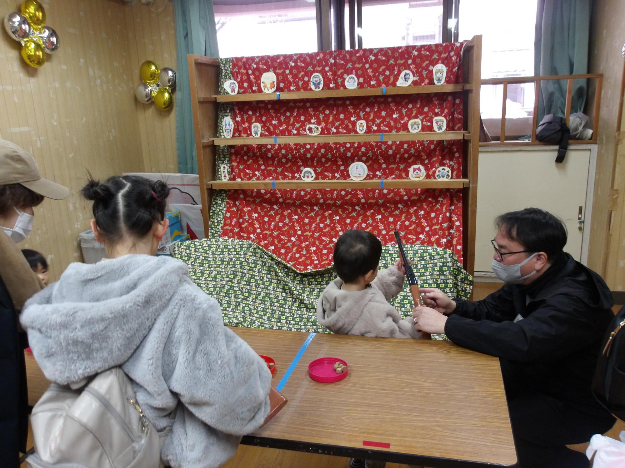 スタッフに射的の説明を受けている子どもの写真