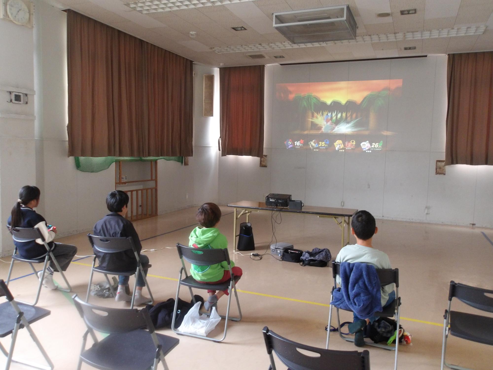 プロジェクターの大画面でゲームをする4人の参加者