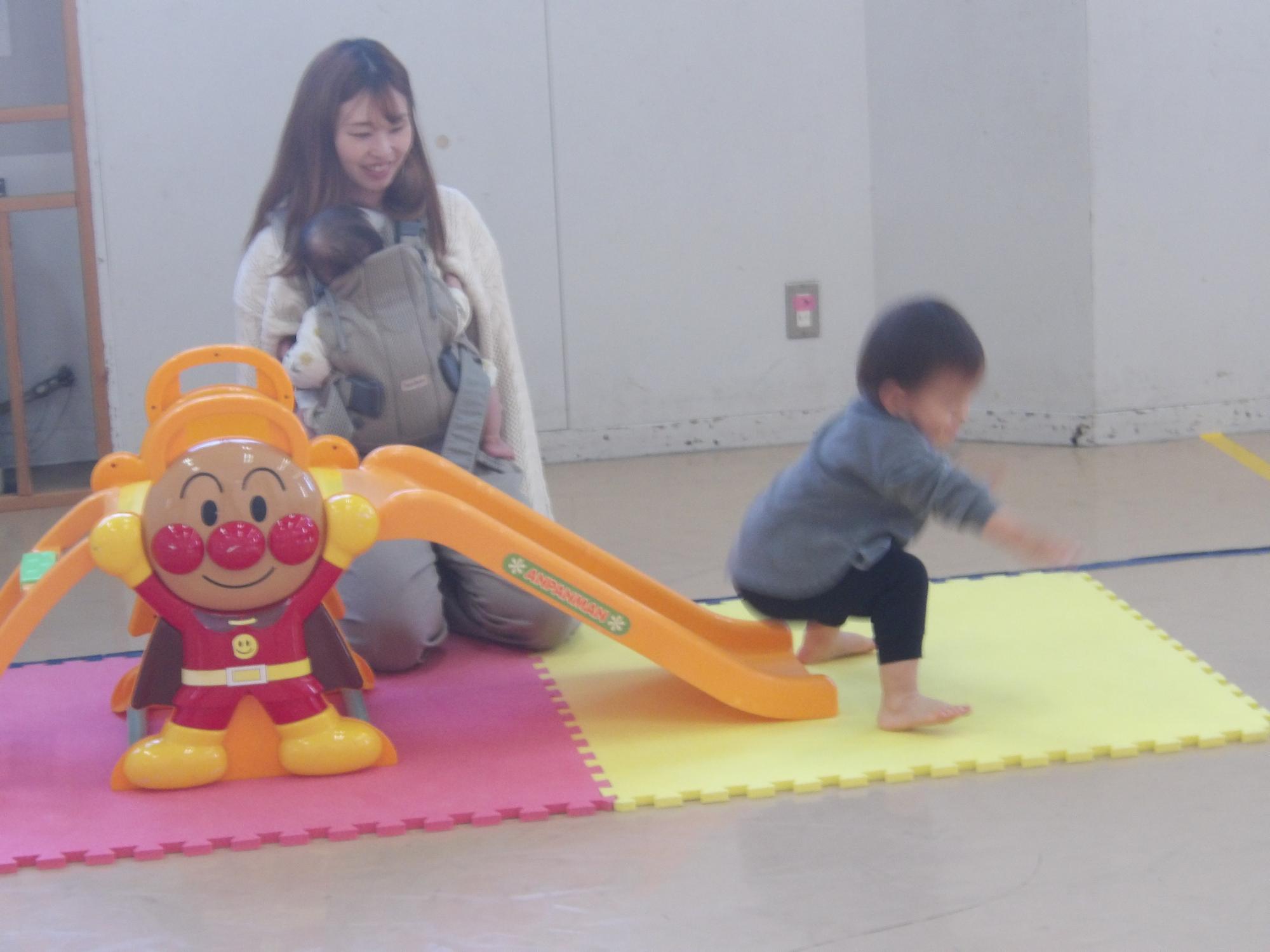 親子でミニすべり台を滑っている様子