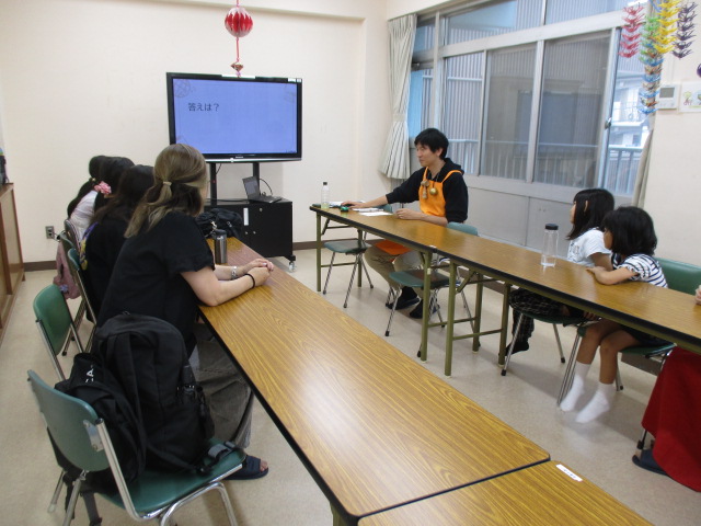 テレビの画面を見ながら講師の話を聞いている子どもとその保護者の様子の写真