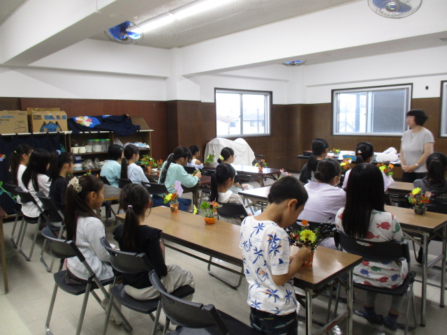 児童生花・茶道クラブで生花の作品を眺めている様子の写真