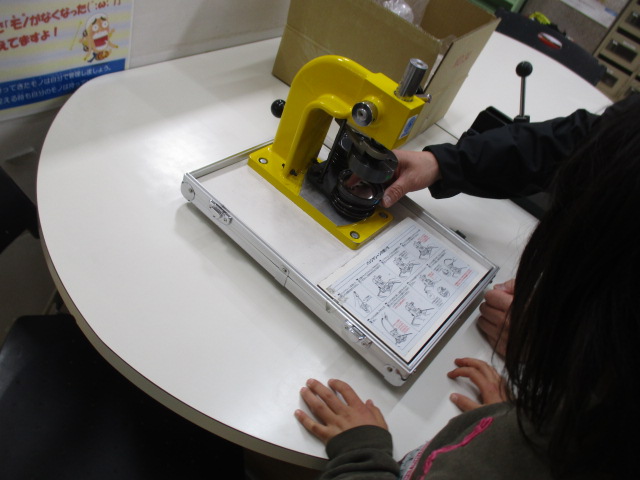 缶バッチを作っている子どもと職員の様子の写真