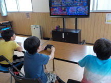 モニターに映ったゲームを楽しんでいる3人の男の子の写真