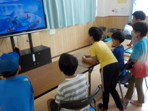 ゲーム画面を一点に見つめ白熱する6人の子供たちを撮影している写真