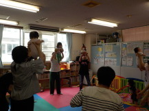 乳幼児をたかいたかいする3組の父親や母親を撮影している写真