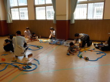 施設内の床にレールを敷いていく参加者たちを全体的に撮影した写真