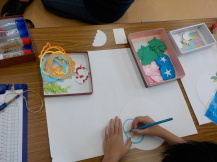 丸い画用紙に青い色鉛筆で絵を描いている写真