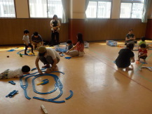 室内のいろいろな場所でプラレールつくりをしている子供たちを左前方から写した写真