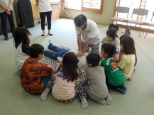 講師の方が人形に心臓マッサージをしているところを子供たちが見ている写真