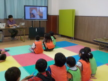 子供たちがモニターの画面を座って見ている写真
