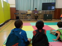 子供たちが講師の方が見せているイラストを見ている写真