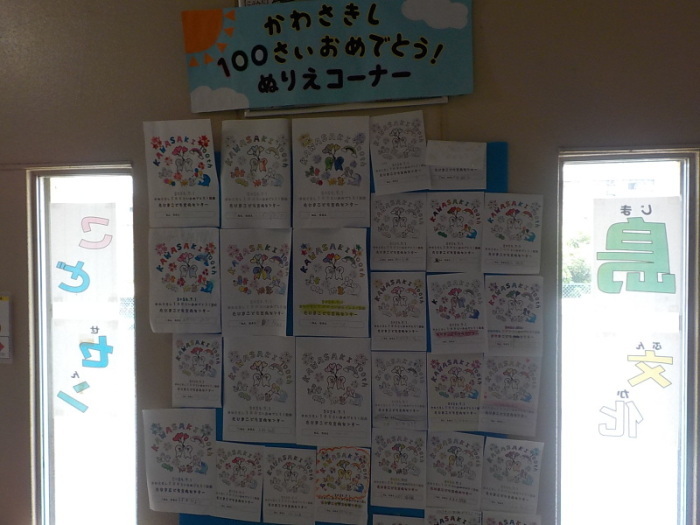 「かわさきし100さいおめでとう！ぬりえコーナー」の下にたくさんの100周年ぬりえが展示されている写真