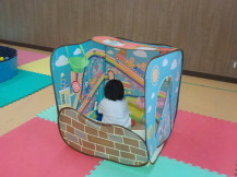 回りに絵が描かれた立方体のテントに幼児が入っている写真