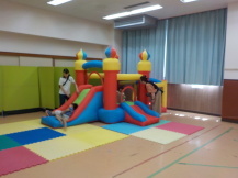 空気が入ったすべり台で遊んでいる1組の幼児親子の写真