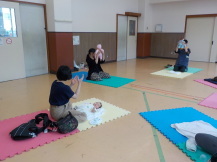 たかいたかいをしている2組の親子を見て話をする母親の写真
