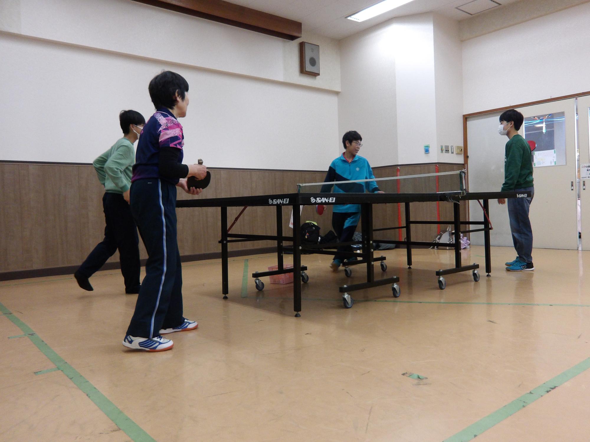 中学生が講師の先生と卓球対戦をしている写真