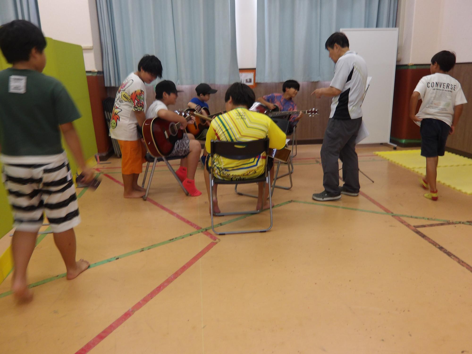 子どもたちが囲んでギターを弾いている写真
