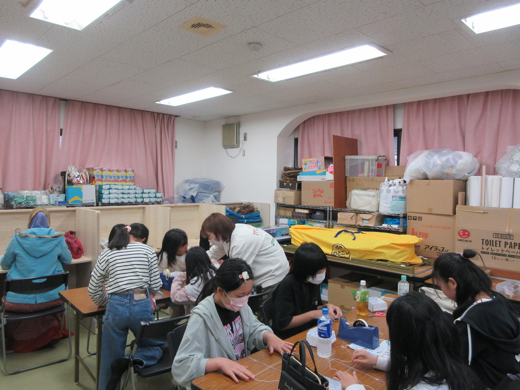 小学生と保護者がアクセサリーを作っている様子の写真