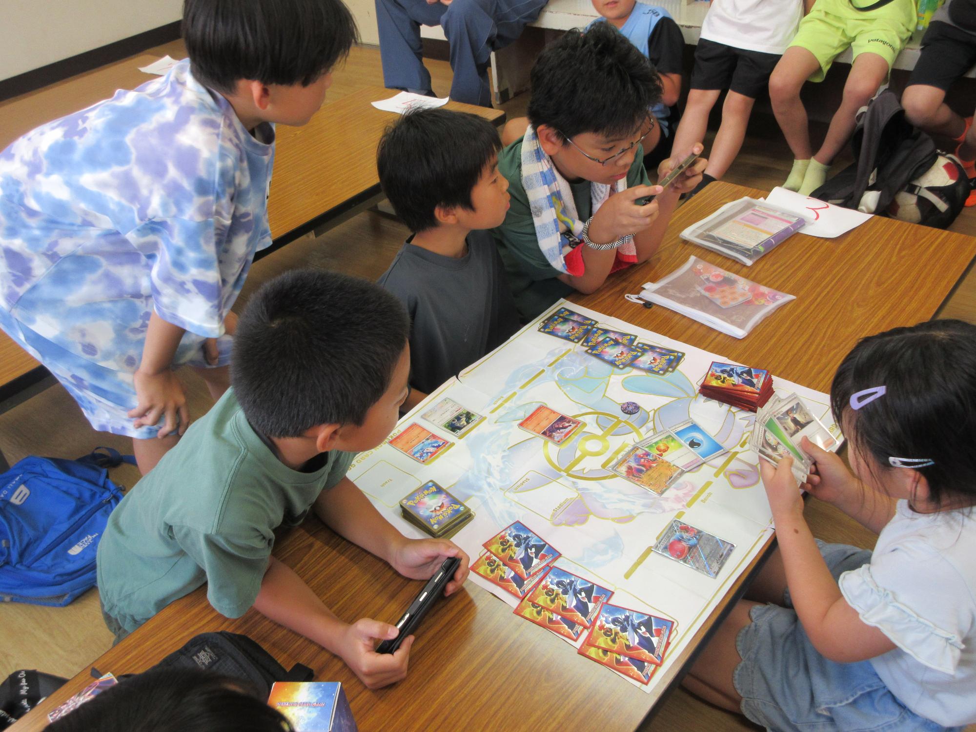 ポケモンカードで対戦する子どもと見学者の様子の写真