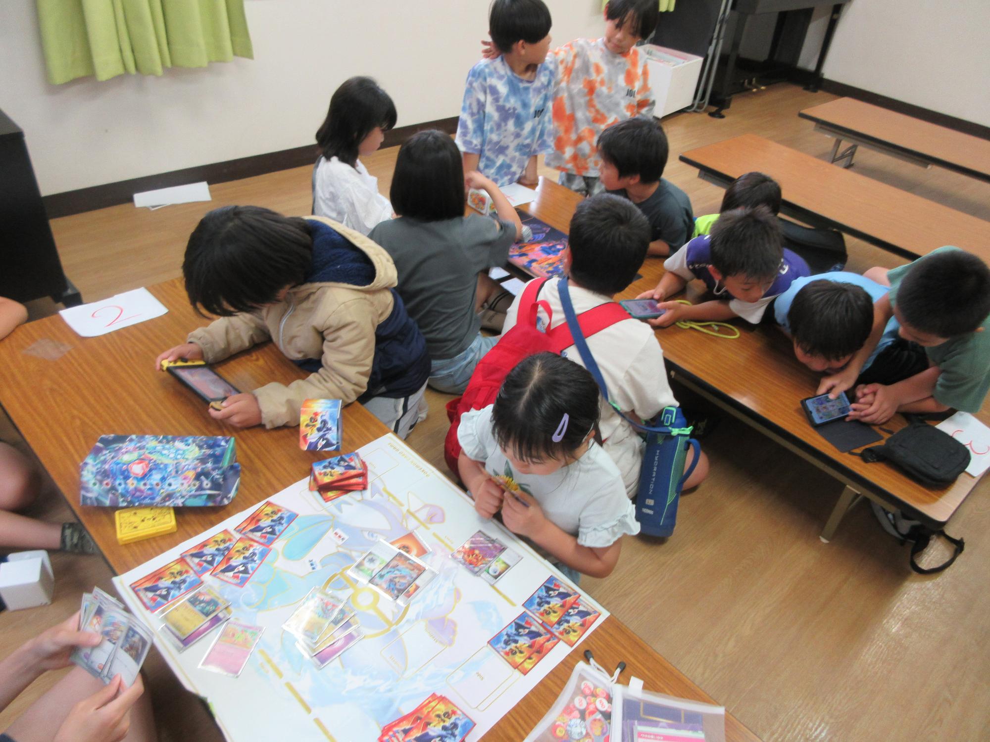 ポケモンカードで対戦する子どもと見学者の様子の写真