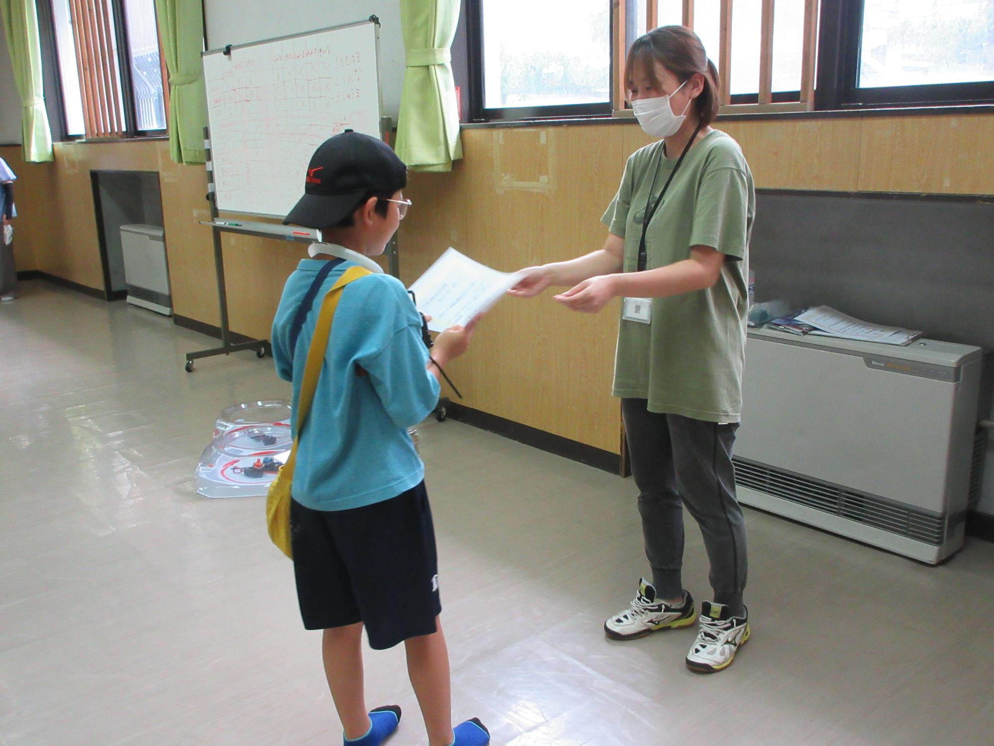賞状を渡す職員と受け取る小学生の様子