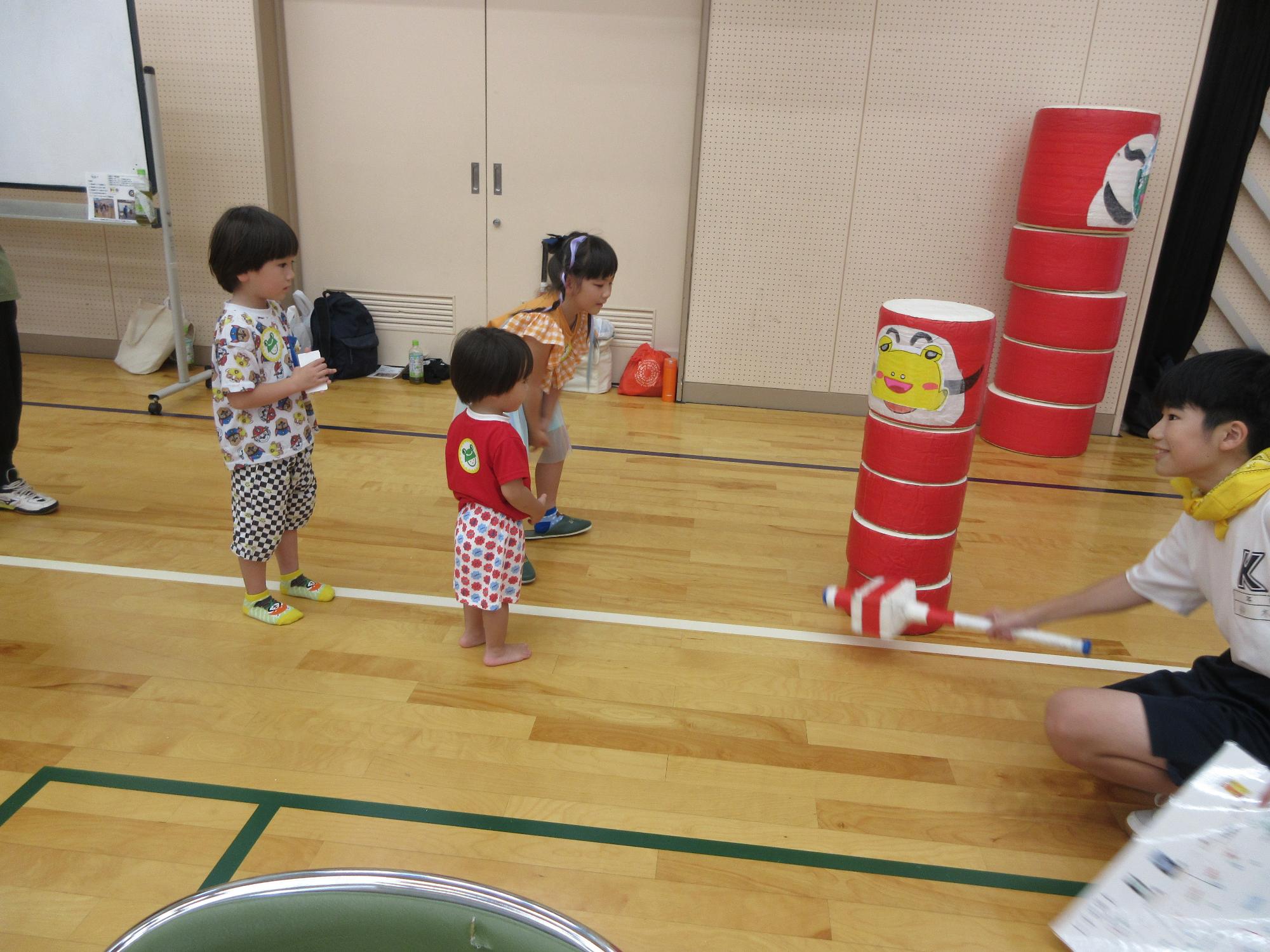 幼児さんたちがだるま落としを教わっている様子