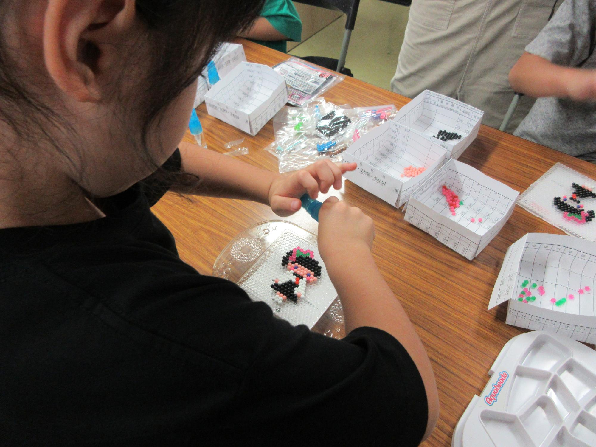 児童たちがビーズストラップ作りをしている様子