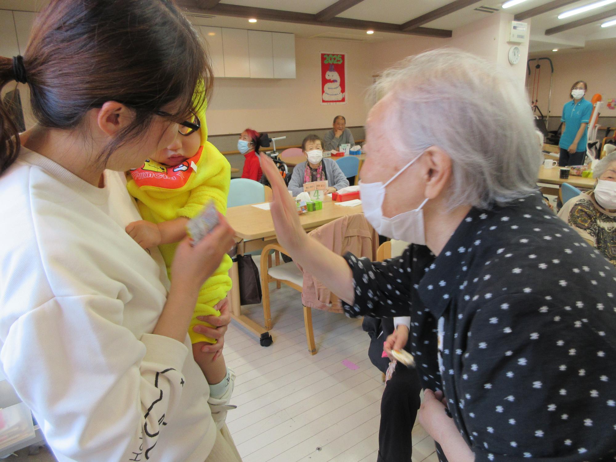 デイサービスの方が乳児さんに手を振っている様子