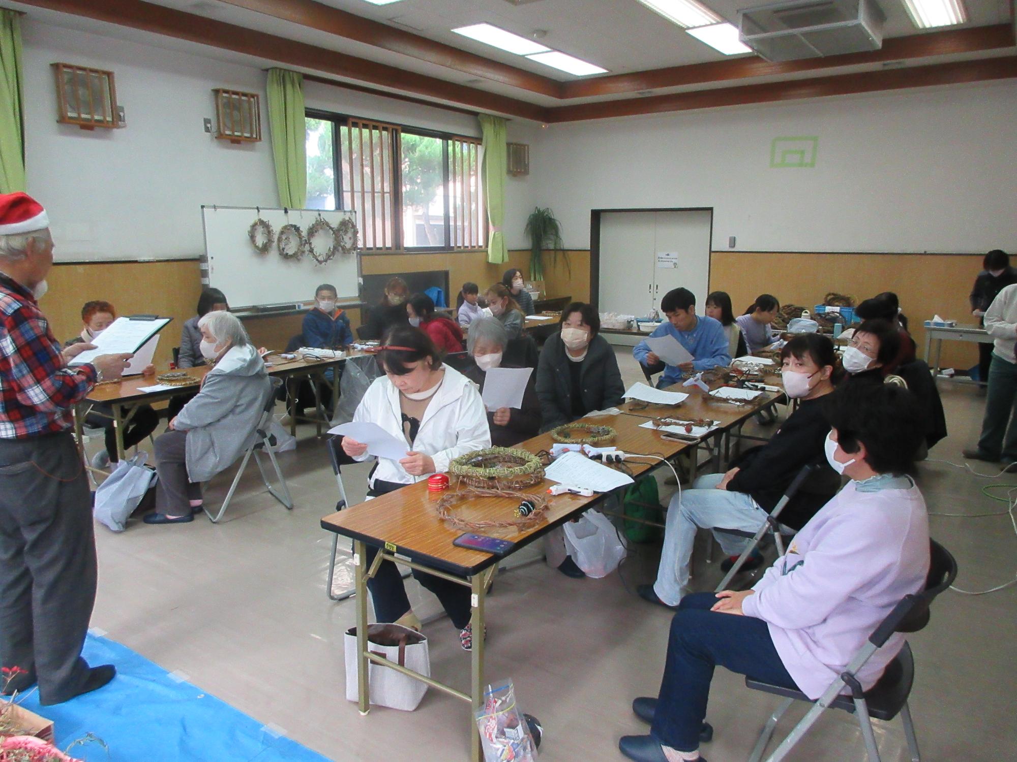 リースづくりの説明をする講師と、説明を聞く参加者の様子