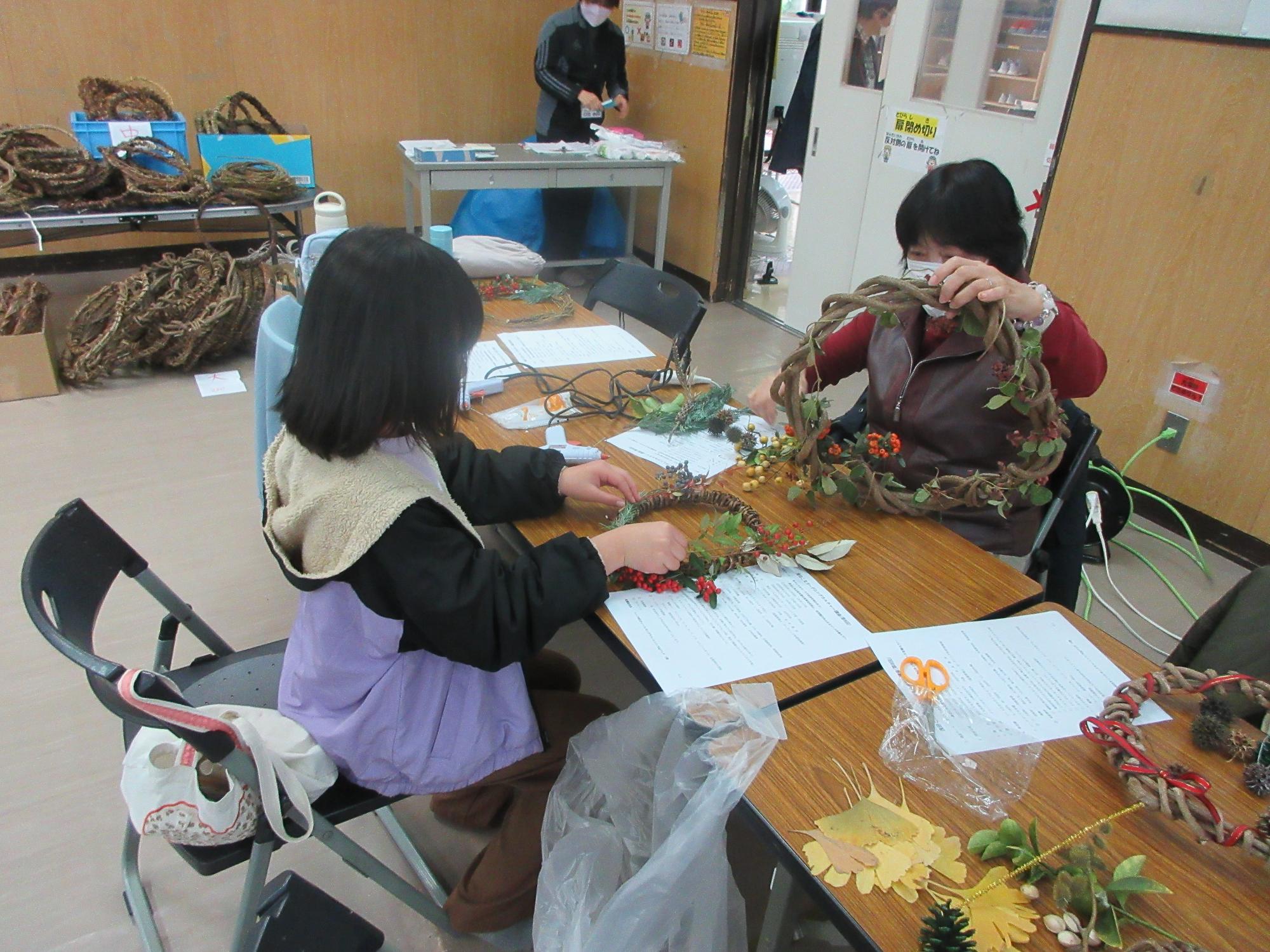 リースの飾り付けをする児童と成人の様子