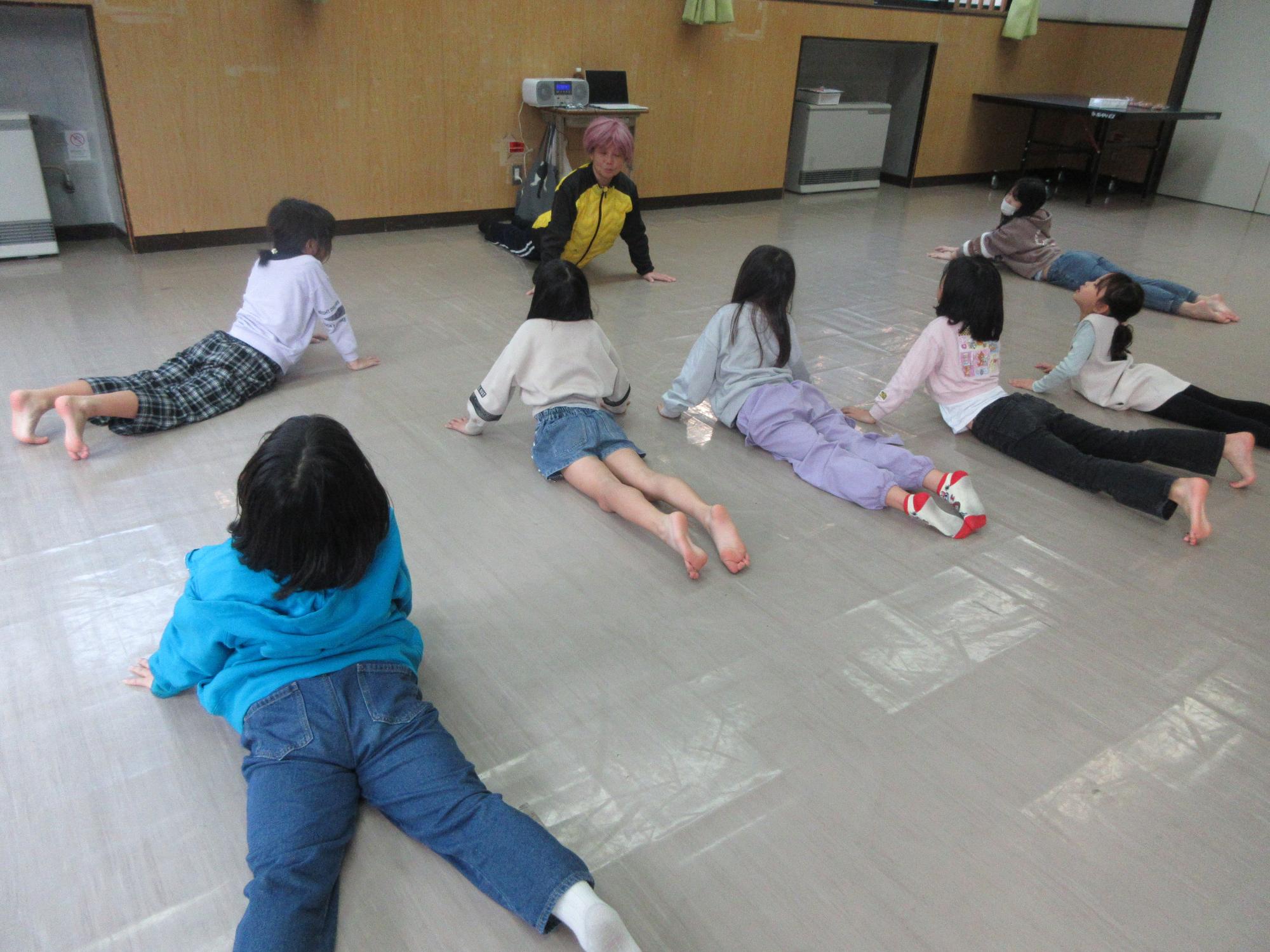 柔軟体操をする児童と指導する講師