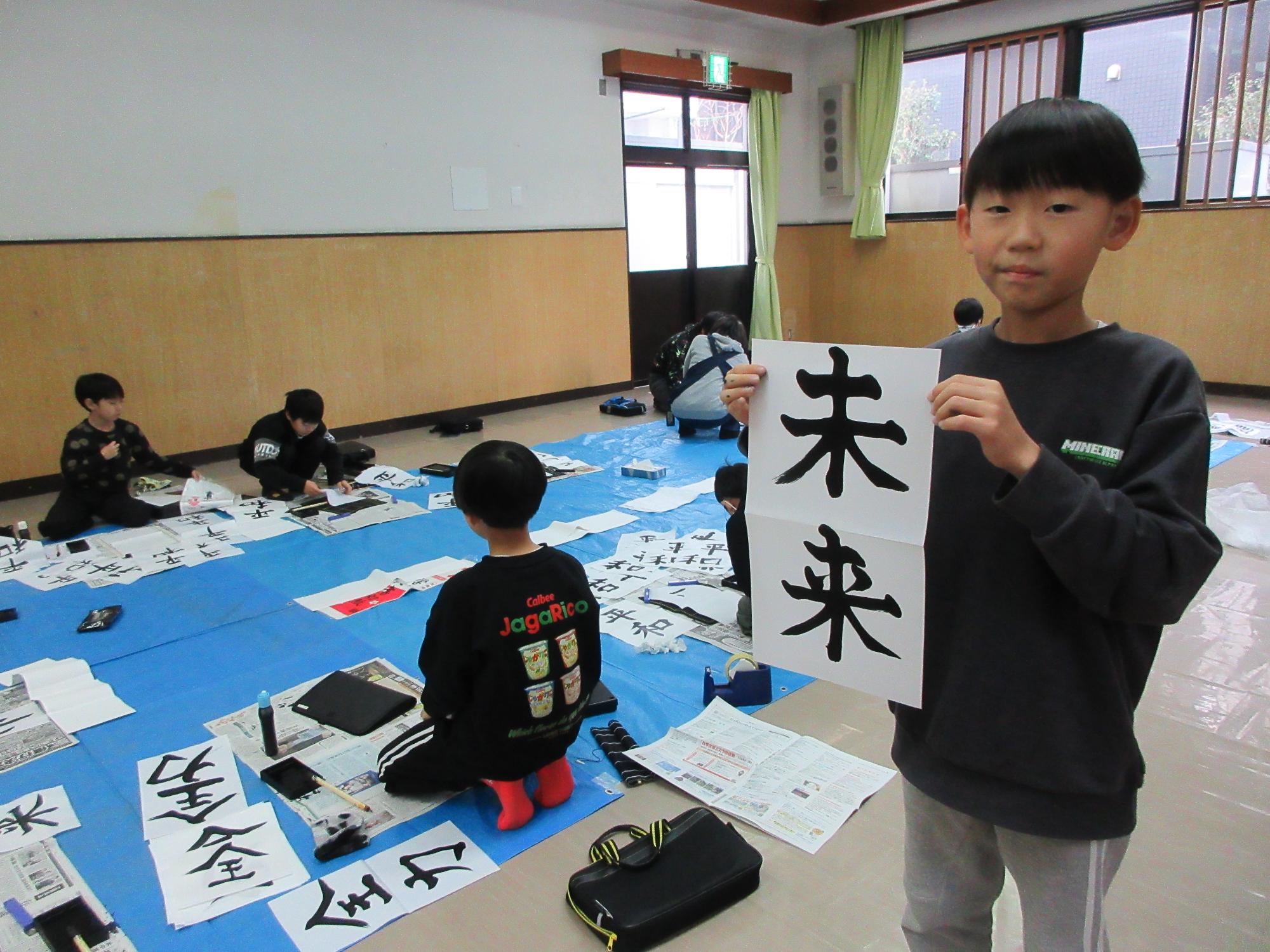 完成した書き初めと参加児童の写真