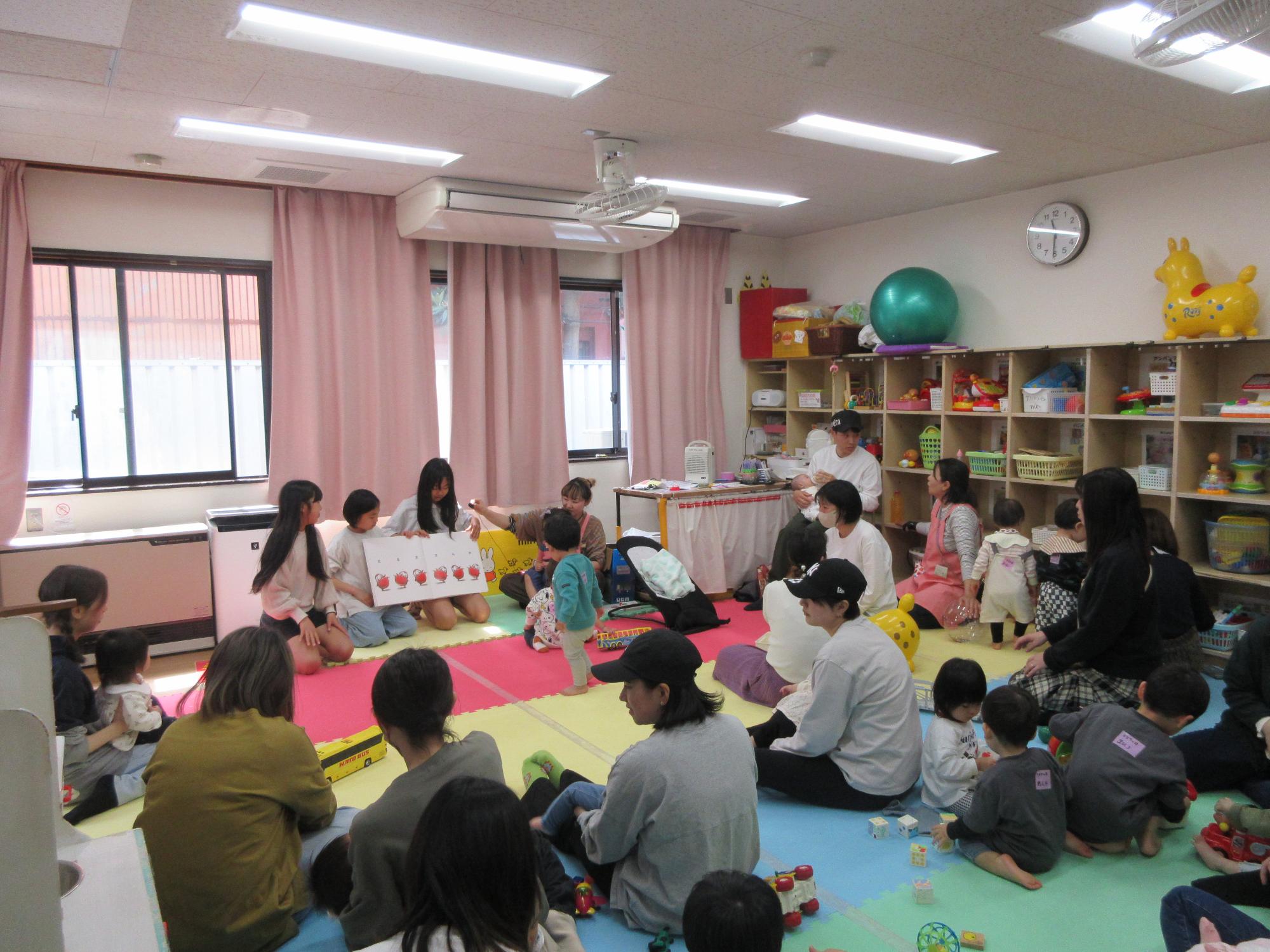 児童が乳幼児親子たちに読み聞かせをしている様子