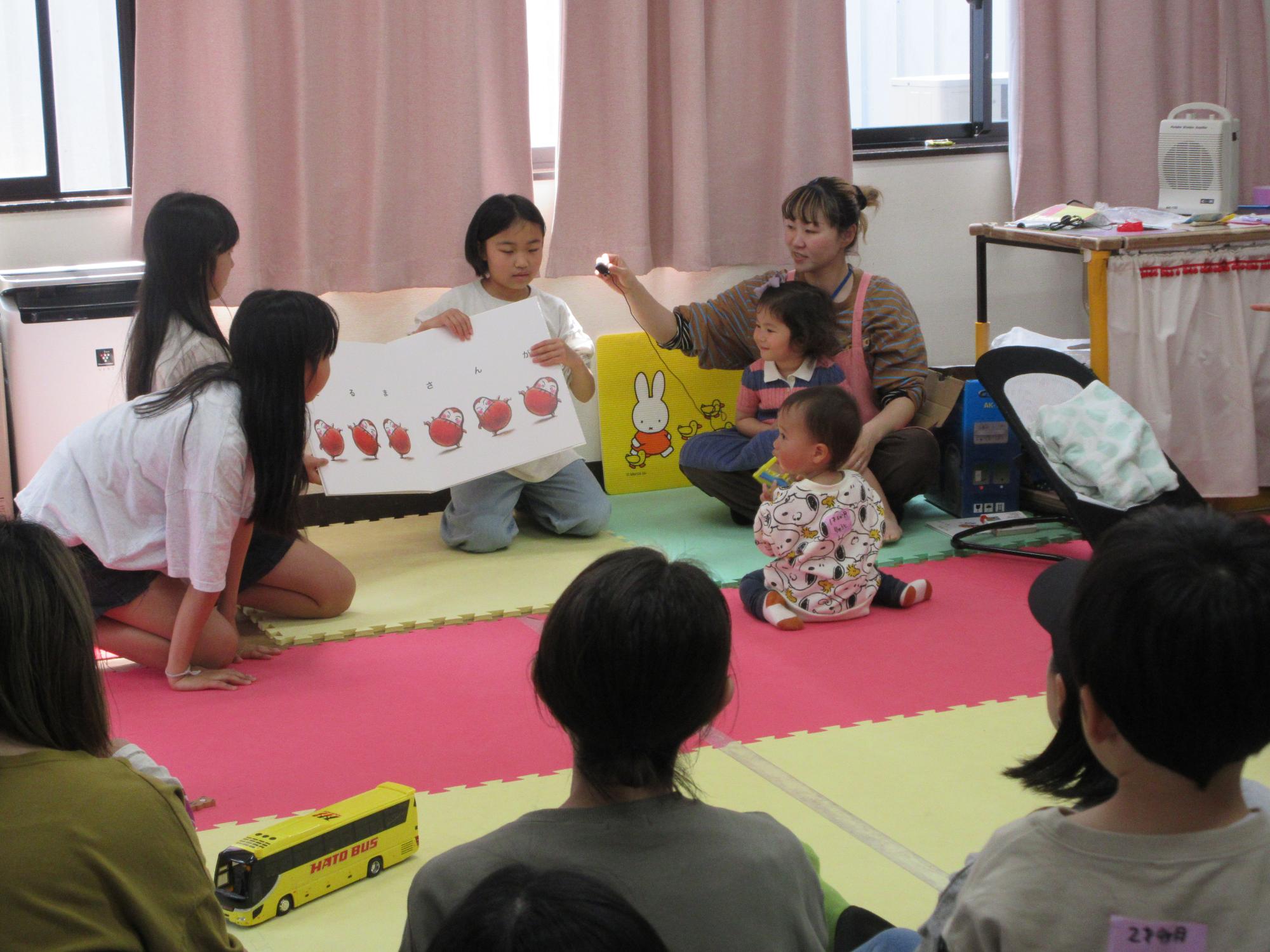 児童が乳幼児親子たちに読み聞かせをしている様子