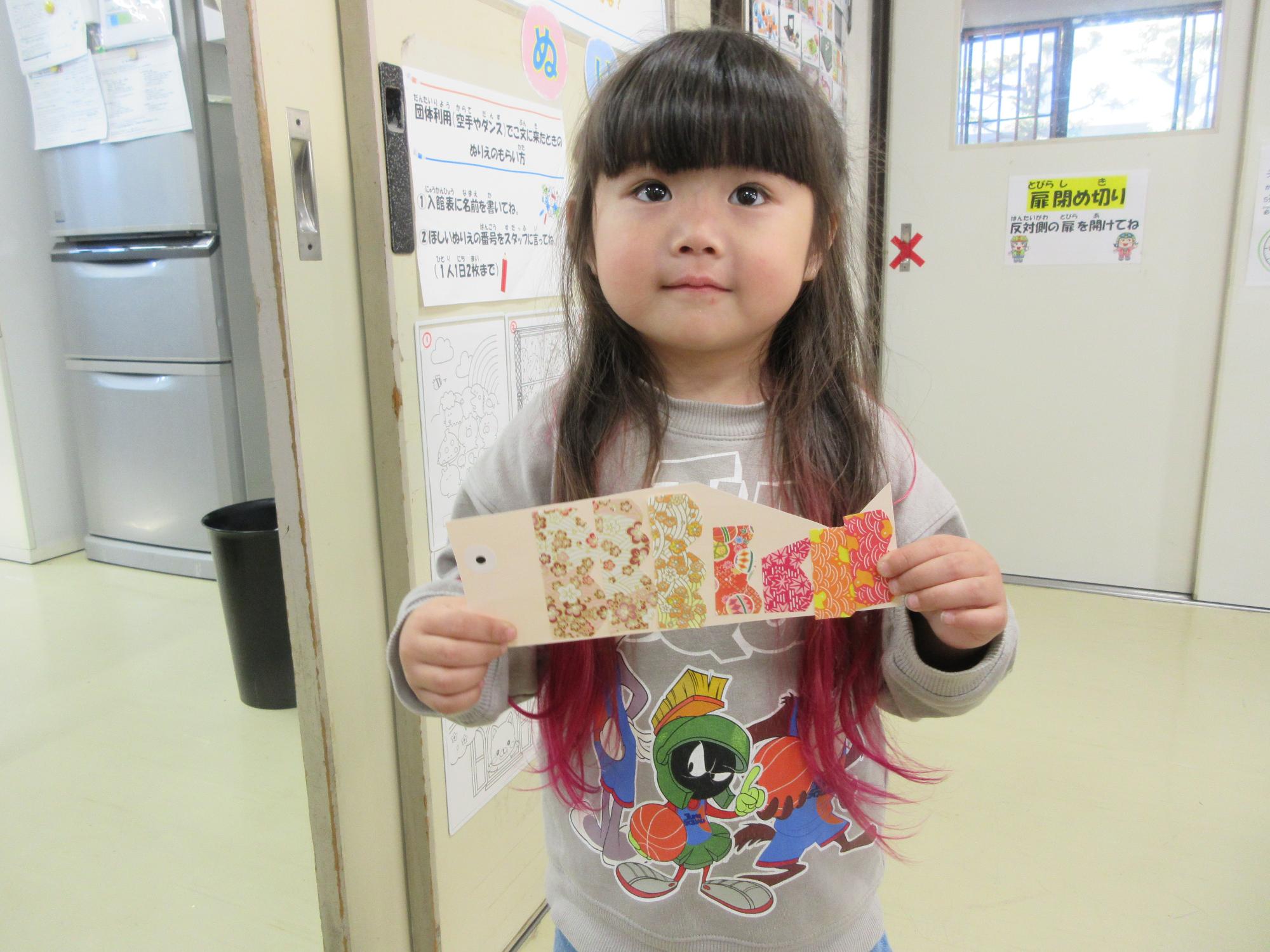 色画用紙で作ったこいのぼり製作を持つ児童の写真