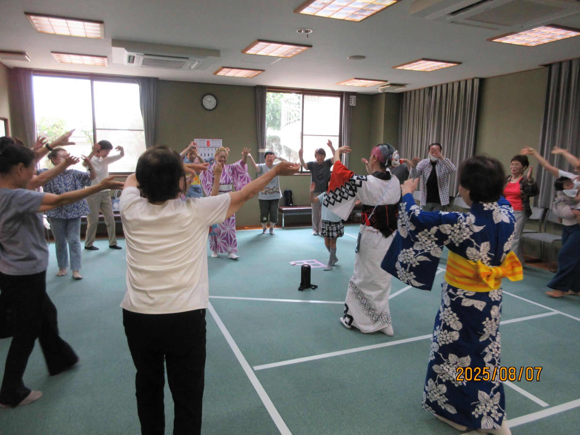 いこいの家の大広間に集まり盆踊りを楽しんでいるところの写真