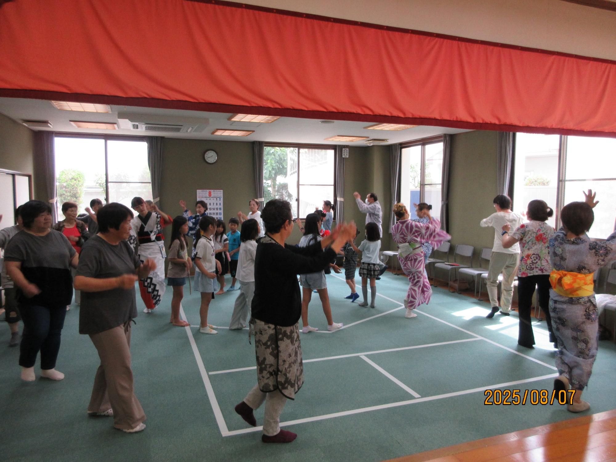 いこいの家の大広間に集まり盆踊りを楽しんでいるところの写真