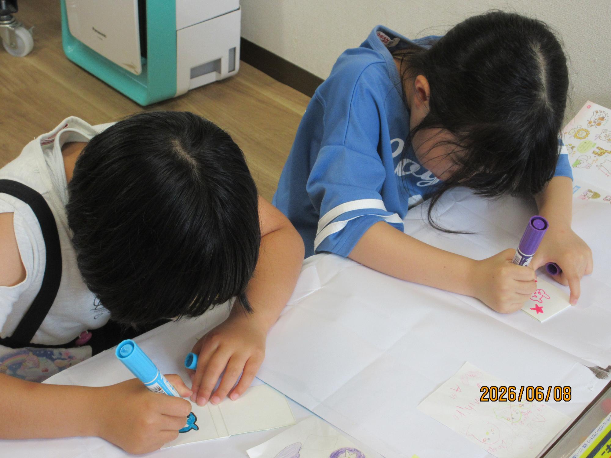 小学生が牛乳パックの紙に絵を描いている様子