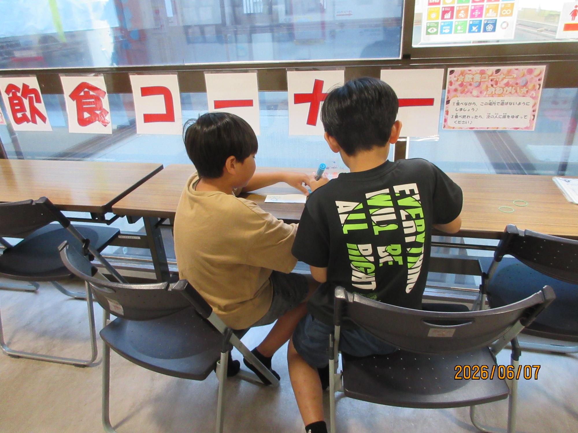 小学生が牛乳パックの紙に絵を描いている様子