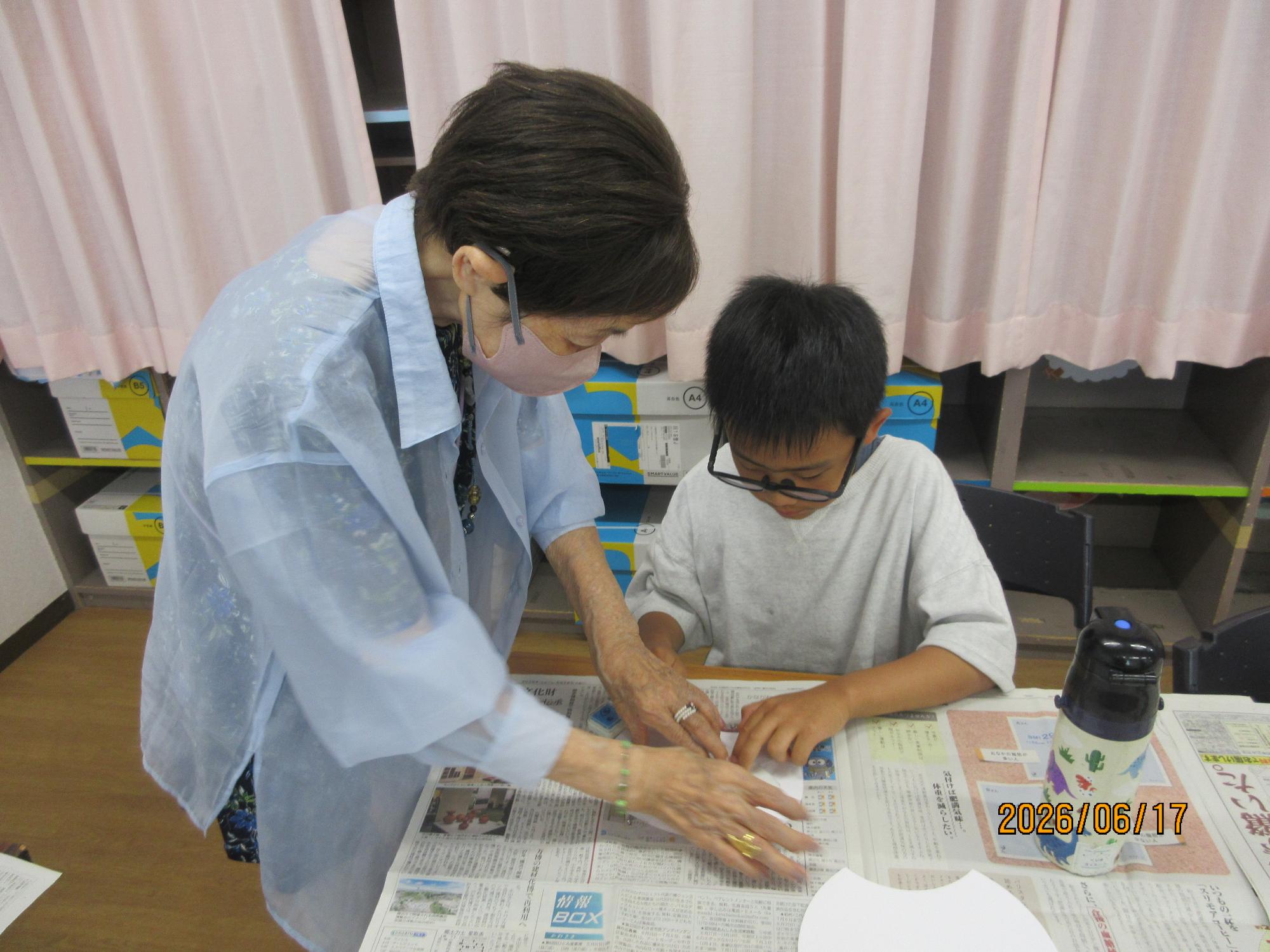 子どもが学習室で先生と一緒に内輪にスタンプをおしているところ