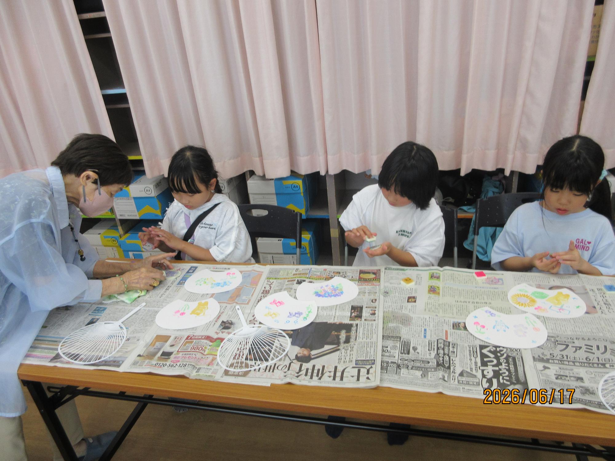 子どもたちが学習室で講師の先生から内輪の作り方をきいているところ