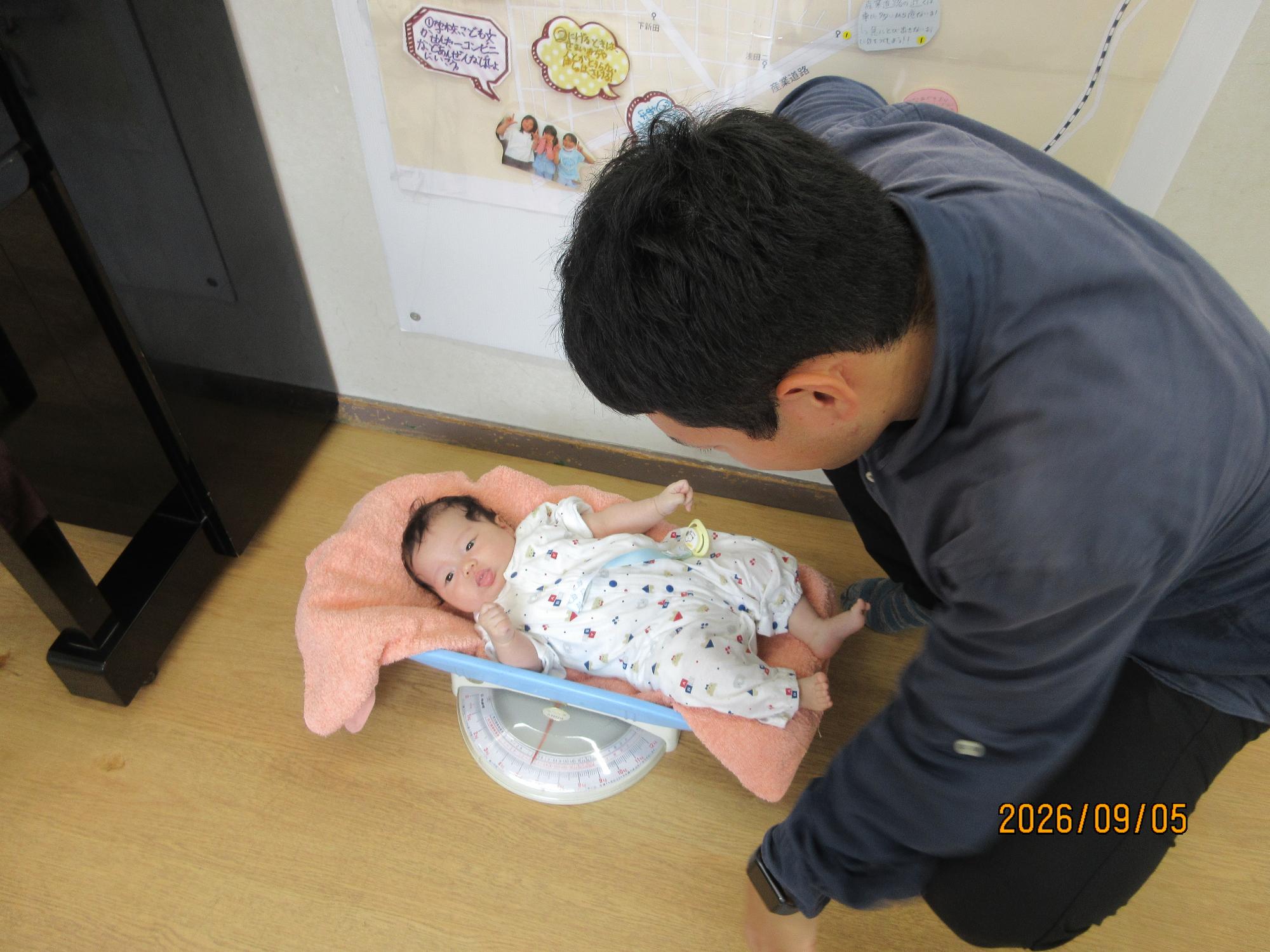 遊戯室で乳幼児さんがお父さんと体重を測っている時の様子