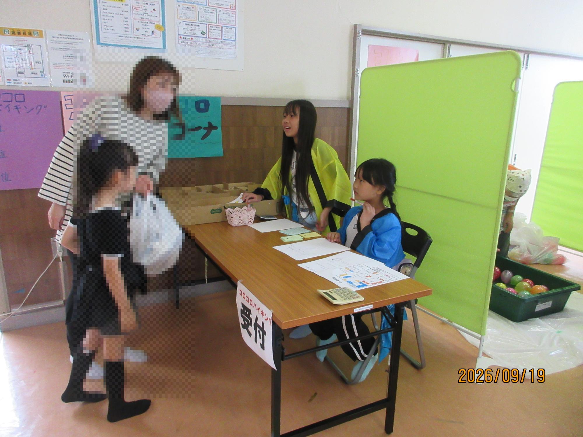 子どもたちが集会室でおまつりのブースをお手伝いしているところの写真