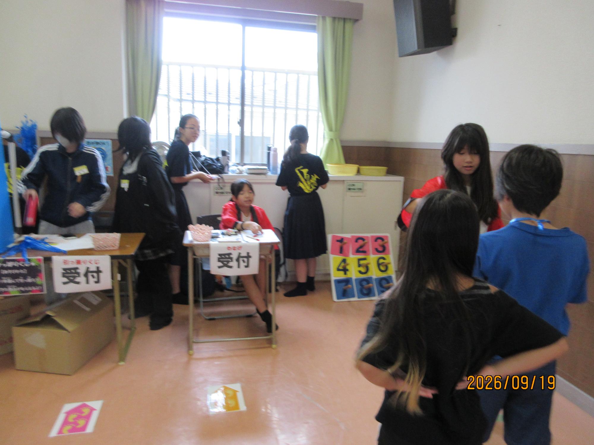 子どもたちが集会室でおまつりのブースをお手伝いしているところの写真