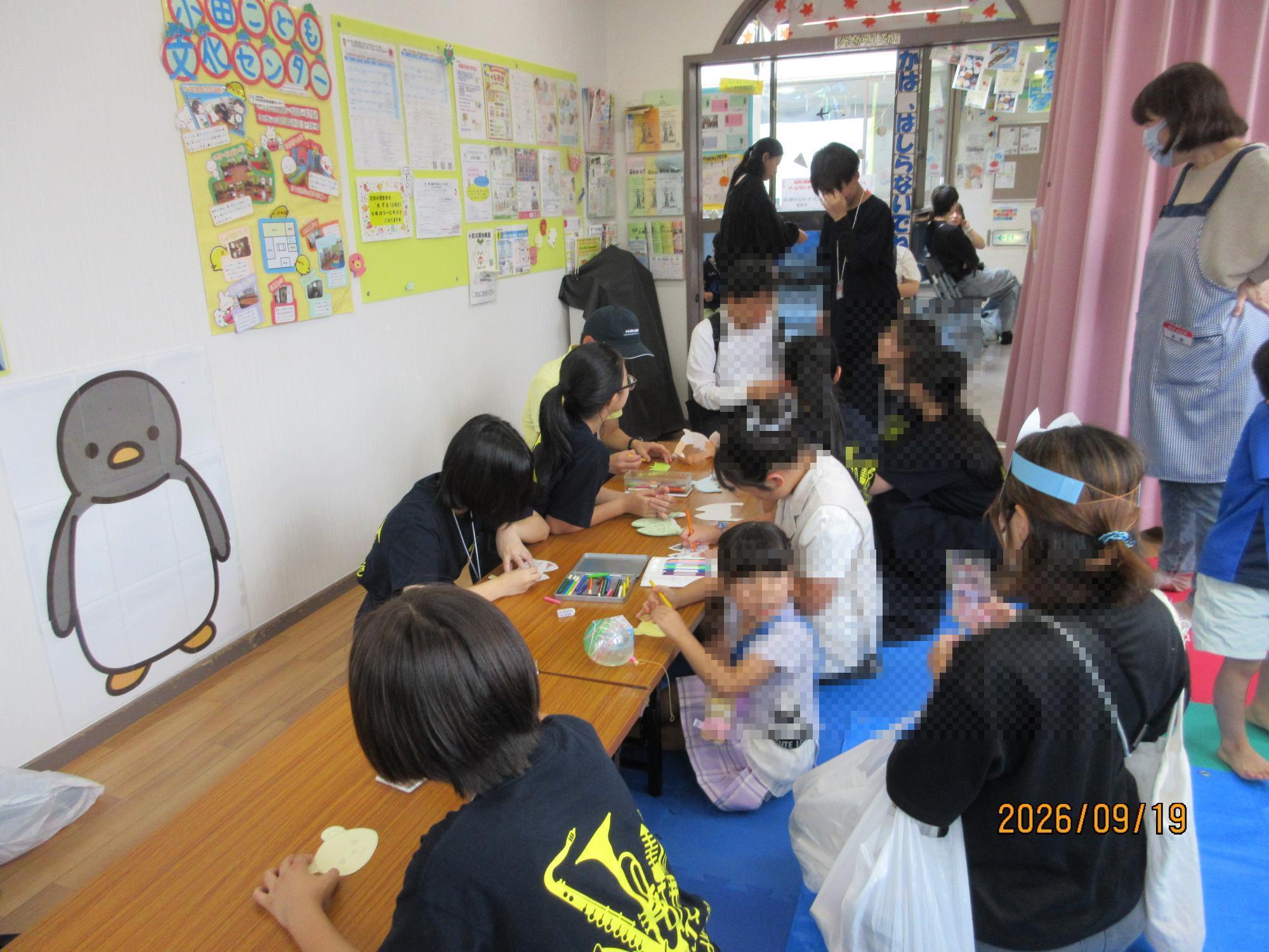 乳幼児親子がお祭りで工作作りをしているところの写真