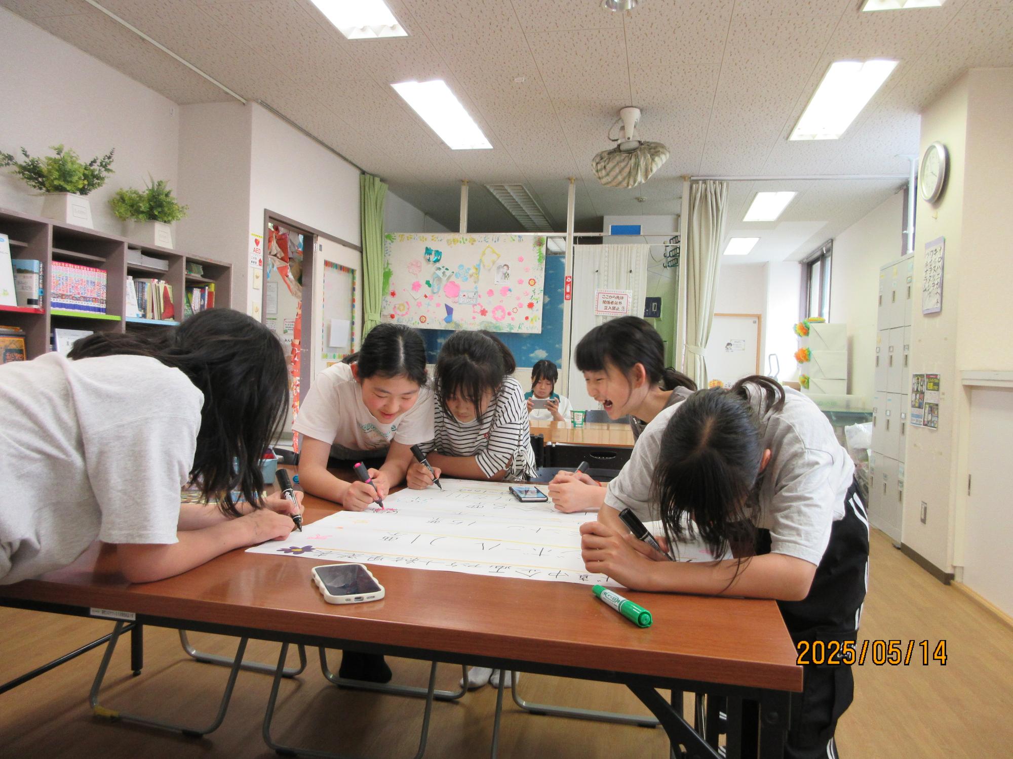 学習室で話をしながらポスターづくりをしているところの写真