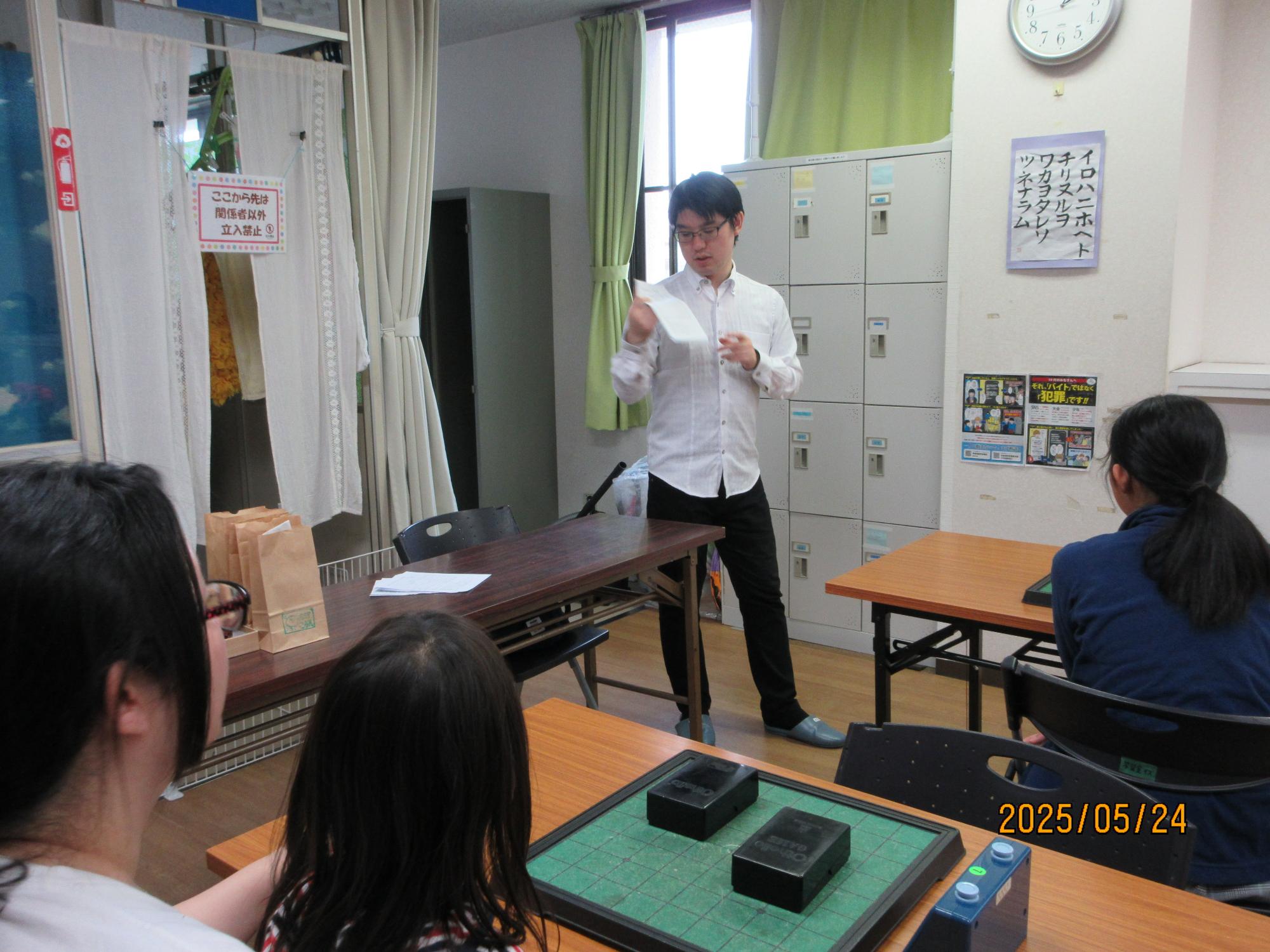 学習室でオセロ大会の説明を講師の先生がしているところの写真